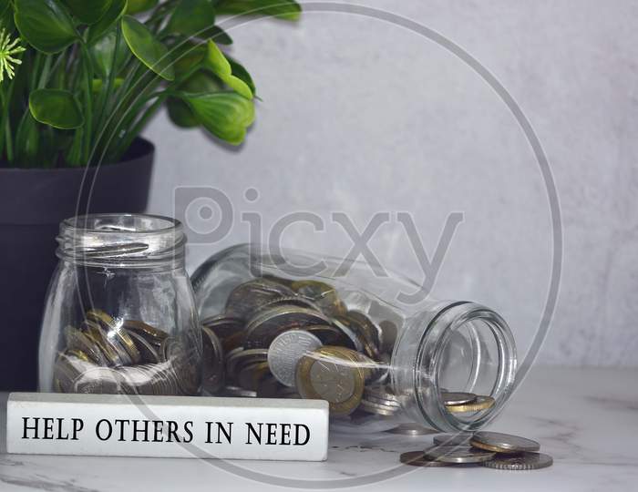 Text on wood block with Australian and European coins on table surface with plant background - Help others in need. Charity concept