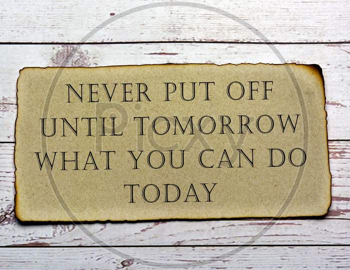 Motivational and inspirational quote on paper with burnt edge - Never put off until tomorrow what you can do today