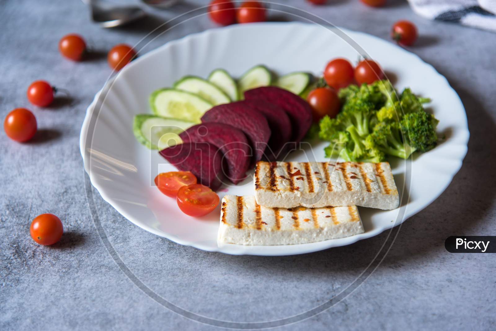 Close up of  grilled paneer or cottage cheese with boiled vegetables on a plate