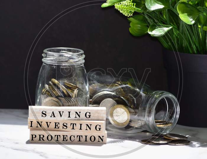 Text on wood block with Australian and European coins on table surface with dark background - Saving, investing and protection. Personal finance concept