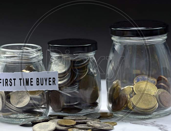 Glass jars with multicurrency coins and text - First time buyer. Home buyer concept