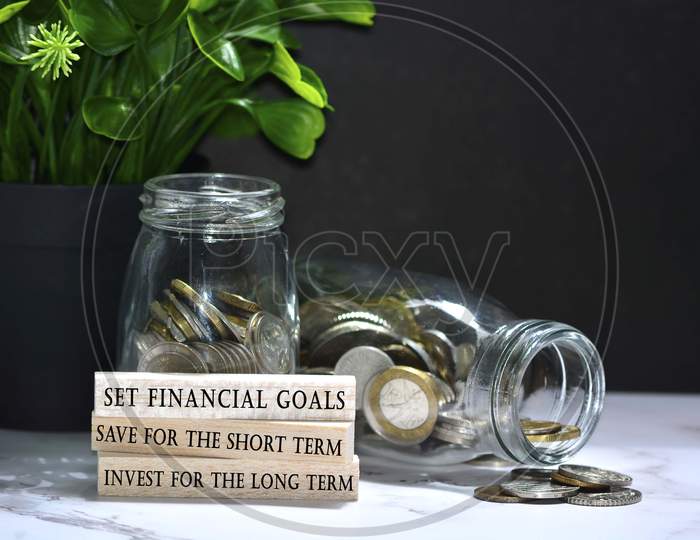 Text on wood block with Australian and European coins on table surface with dark background - Set financial goals, save for the short term and invest for the long term. Financial plan concept