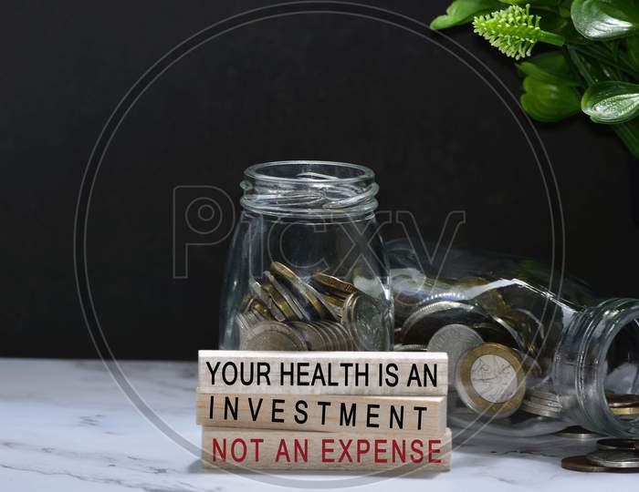 Text on wood block with Australian and European coins on table surface with dark background - Your health is an investment not an expenses. Health investment concept