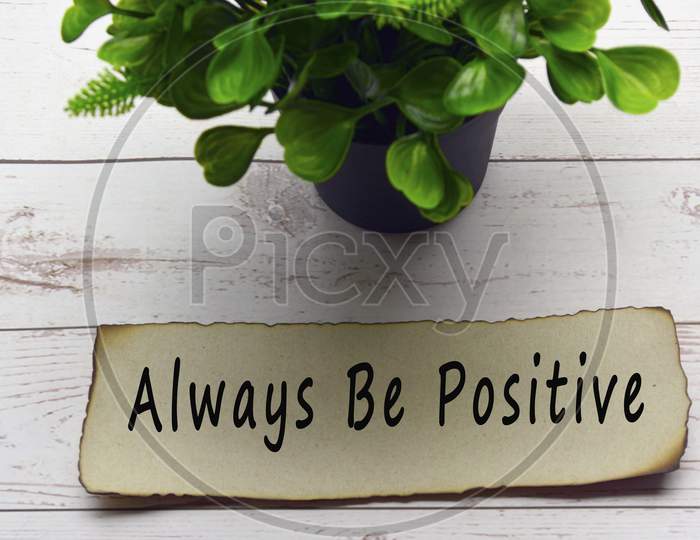 Motivational and inspirational quote on burnt edge brown paper with blurred plant background on wooden desk