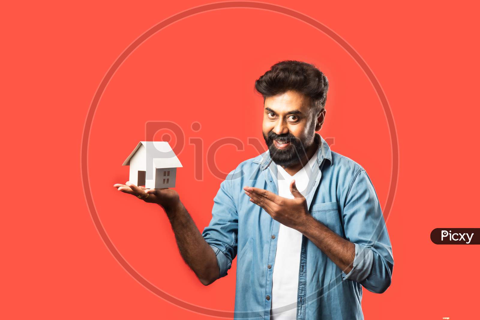 Indian Asian Bearded Young Man Holding Paper House Model With Keys And Piggy Bank