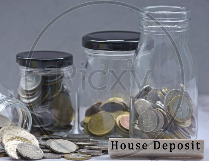 Text on wood block and glass jars with multicurrency coins. Blurred background
