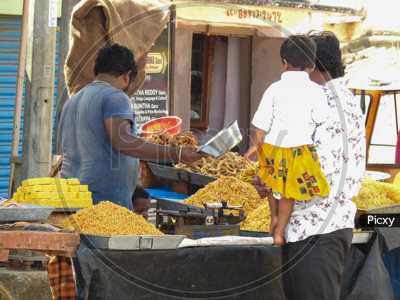 Closeup Of Roadside Sweets And Fried Food Selling In A Cart By Weighing In Traditional Weight Scale.