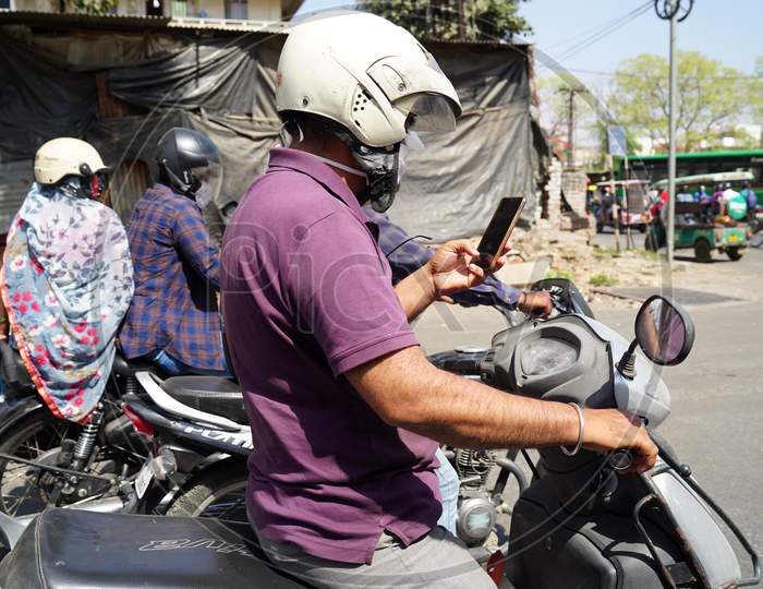 Man Wearing Helmet And Waiting Of Green Traffic Light. Man Passing Time On Cellphone.