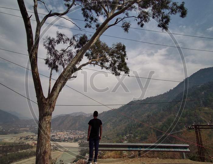 a boy at the hill station looking around the mountains
