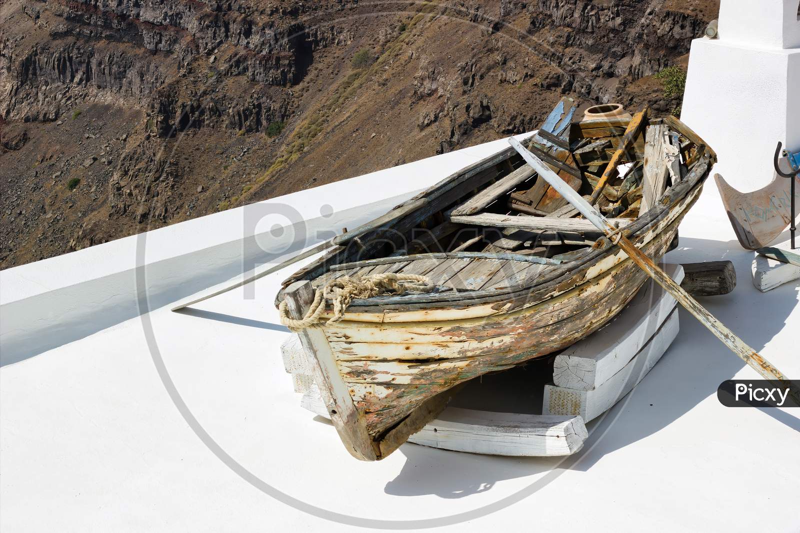 Santorini, Greece: A Wrecked Boat On A Roof At Firostefani Near Fira On A Greek Island Named Santorini. In The Background Is Skaros Rock Mountain Of Imerovigli