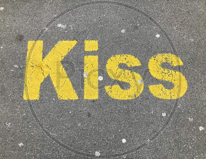 Yellow Kiss Inscription Painted On Asphalt