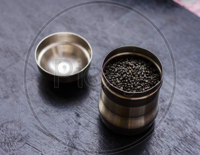 A Steel Jar Full Of Black Lintel Or Kali Dal On A Black Wooden Table.