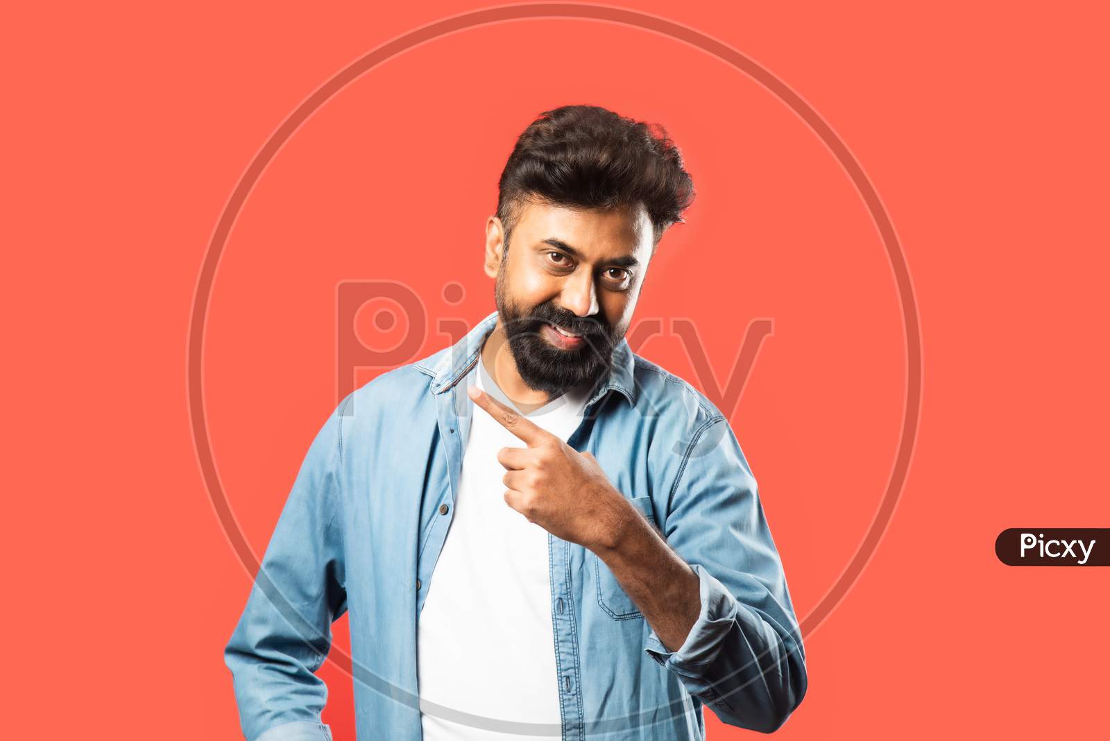 Indian Asian Bearded Man Pointing Or Advertising Blank Space Against Red Background