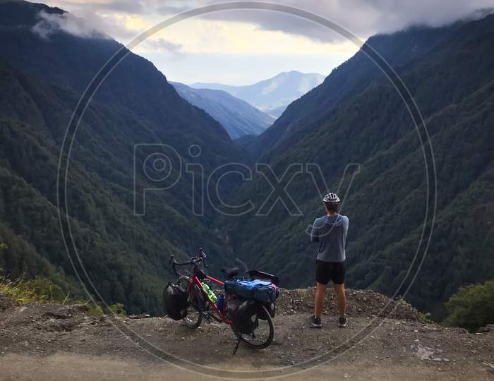 Caucasian Male Cyclist Enjoying Tranquil Mountain Panorama With Touring Bicycle Standing