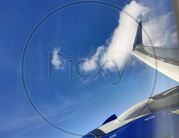 View of the engine on the wing of the aircraft during the flight in the blue sky.