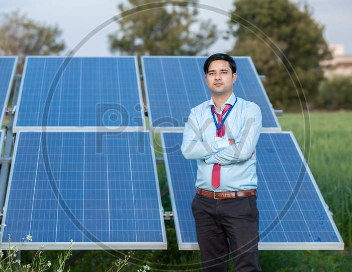 Portrait Young Indian Technician Or Manager Wearing Formal Cloths Standing With Solar Panel. Renewable Energy, Man Standing Crossed Arm, Copy Space.