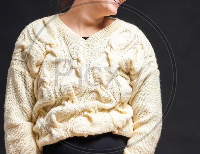 Young Dark-Haired Beautiful Woman In Late Pregnancy With Glasses And Knitted Milk-Colored Sweater Smiling And Holding Her Tummy On A Black Isolated Background