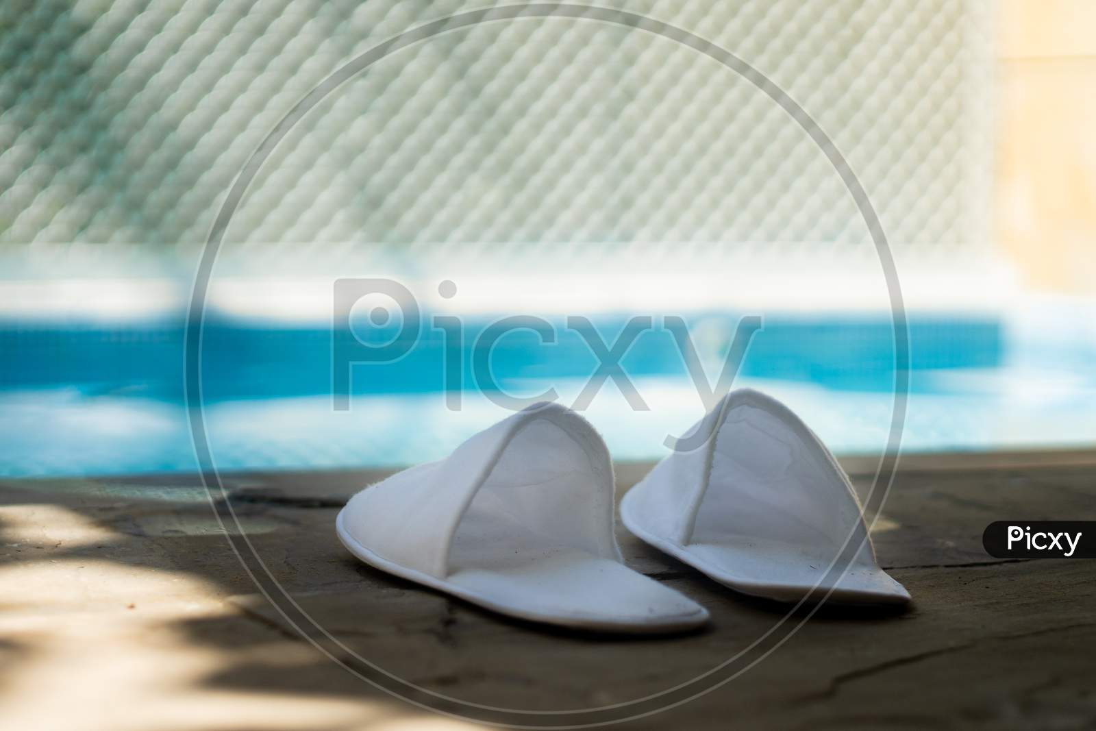 White Cloth Carpet Sippers Placed On The Side Of A Out Of Focus Pool With Light Reflections Playing In The Distance Showing The Luxury And Relaxation Of A Expensive Resort