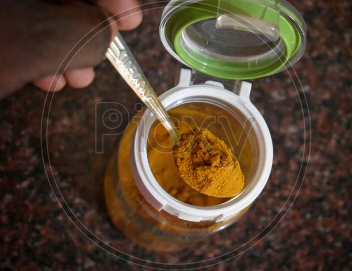 Turmeric (Curcumin) Powder In A Wooden Ladle And Fresh Rhizome On A Red Background,For Spices And Medicine,India.