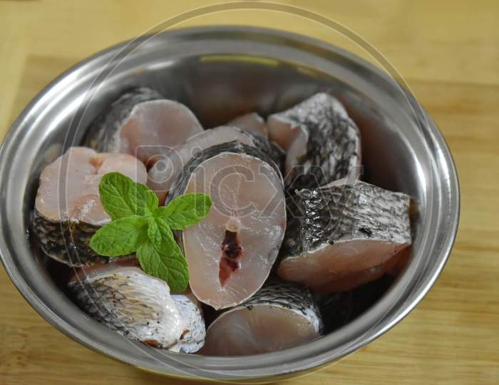Raw Fish Fillet Of Tilapia On A Cutting Board With Lemon And Spices On A Steel Bowl. Cutting Board With Copy Space, India.