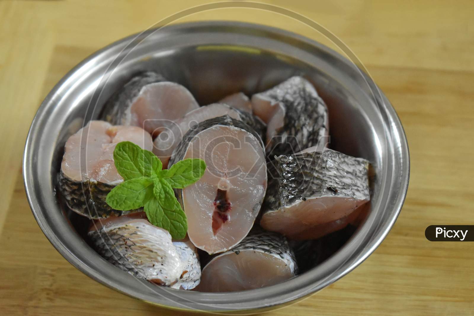 Raw Fish Fillet Of Tilapia On A Cutting Board With Lemon And Spices On A Steel Bowl. Cutting Board With Copy Space, India.