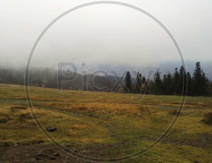 South Poland Landscape Of Trees, Green Grass And Foggy Mist Against Mountains Located In Bielsko Biala, South Poland.