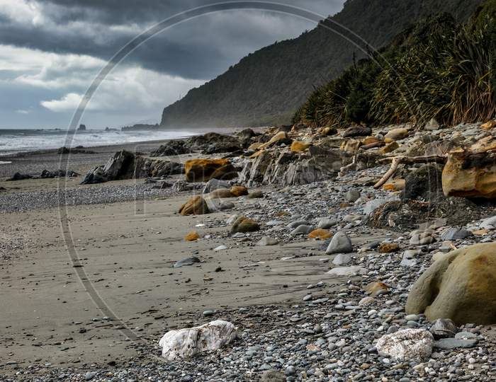 Stormy Weather Approaching A Rock Strewn Beach In New Zealand