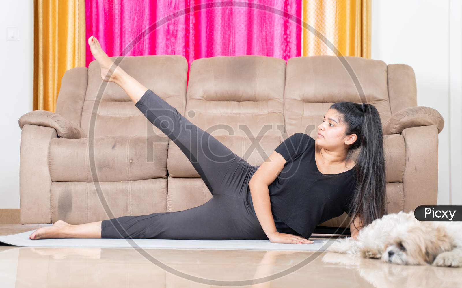 Young Girl With Her Pet Aside Doing Exercise On Yoga Mat At Home - Concept Of New Normal Healthy Lifetyle Due To Coronavirus Covid-19 Pandemic.