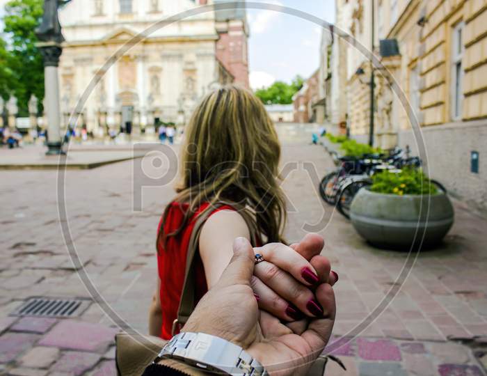 Travel In Famous City Follow Me Woman In An European City Holding Hand Of Boyfriend Or Husband Following Leading Girlfriend Walking. Tourism, Love, Honeymoon And Romantic Travel Concept