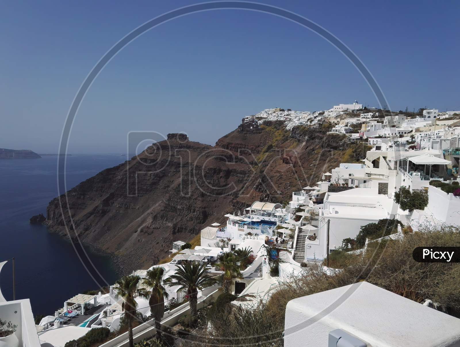 Santorini, Greece - September 11, 2017: Wide Angle Shot Of Santorini Cityscape In The Town Of Oia Against Dramatic Clouds. Small White Houses On Cliff In Famous Greek Island