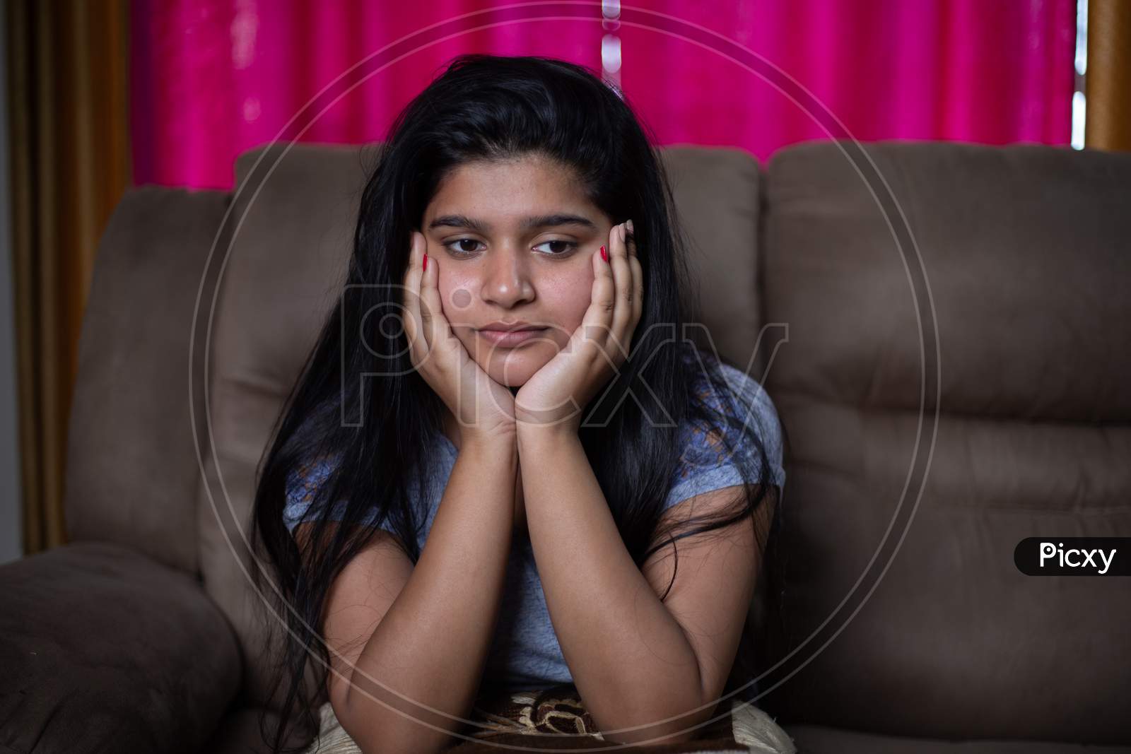 Alone Sad Young Girl Thinking About Problems While Sitting On Sofa - Concept Of Negative Emotions, Mental Health Illness Due To Coronavirus Covid-19 Pandemic.