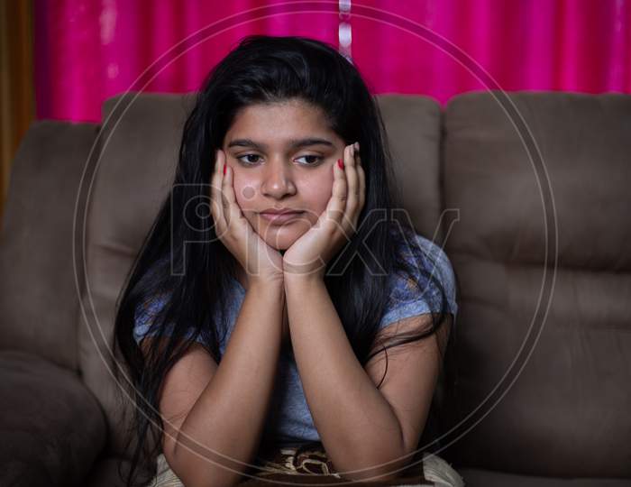 Alone Sad Young Girl Thinking About Problems While Sitting On Sofa - Concept Of Negative Emotions, Mental Health Illness Due To Coronavirus Covid-19 Pandemic.