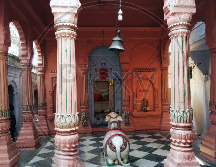Varanasi, India - November 01, 2016: Interior Of A Hindu Temple With Pillars, Stone Diety Bull Nandi And Bell Swinging On Top. Uttar Pradesh.