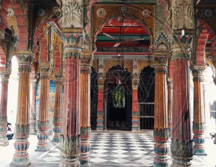 Varanasi, India - November 01, 2016: Interior Of An Empty Ancient Hindu Temple With Stone Carved Design, Pillars With Checker Marble Floor And Bell Swinging On Top. Uttar Pradesh.