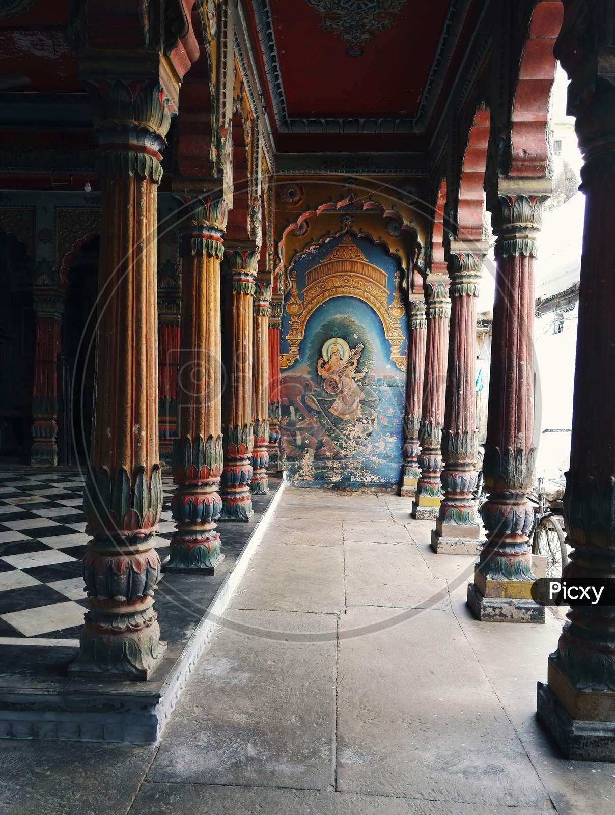 Varanasi, India - November 01, 2016: Interior Of An Empty Ancient Hindu Temple With Stone Carved Design, Pillars With Checker Marble Floor And An Image Of Saraswati Goddess On Wall . Uttar Pradesh.