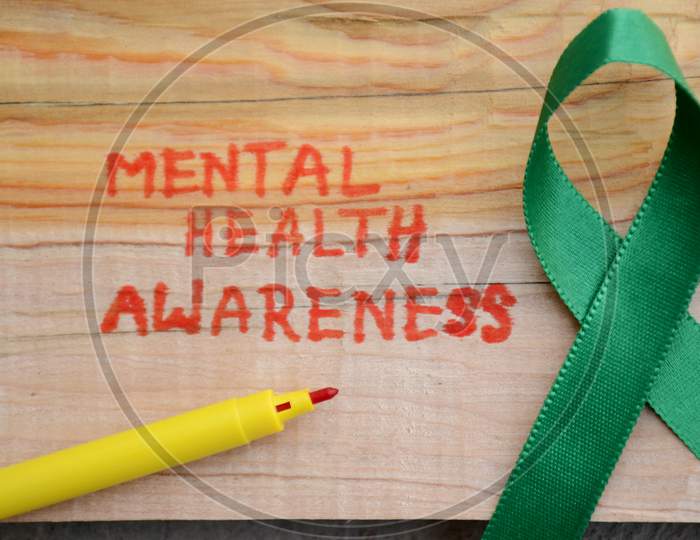 The Green Ribbon Cross With Red Writing Mental Health Awareness Concept On The Wooden Background.
