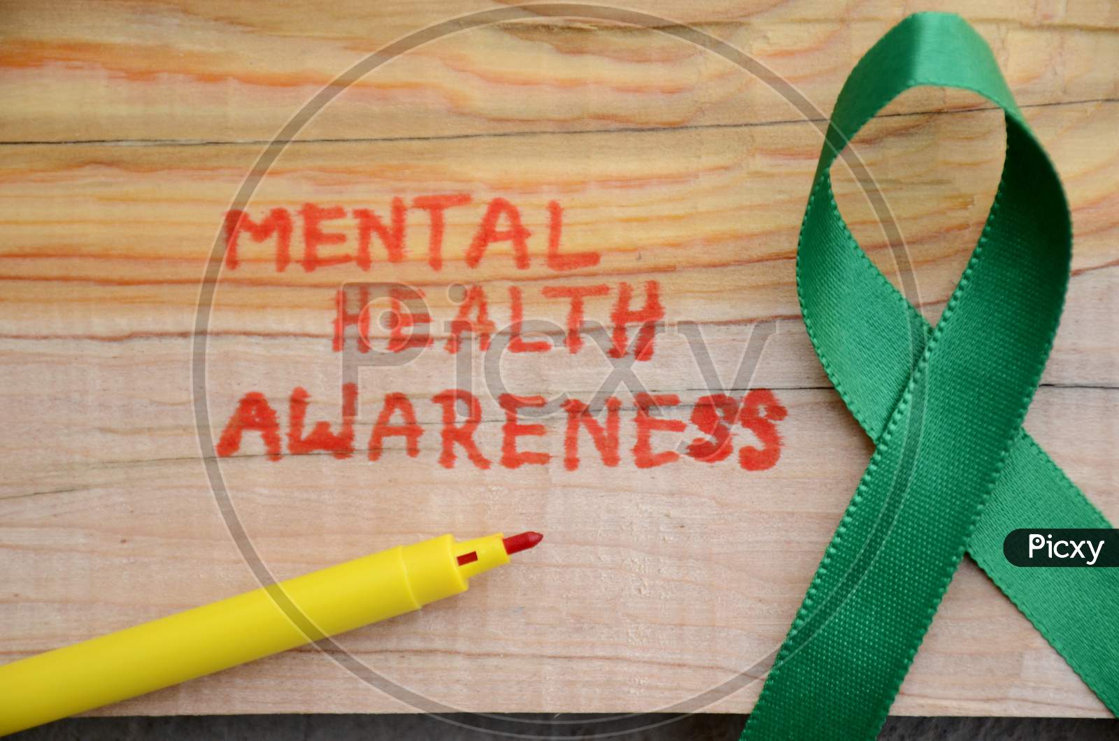 The Green Ribbon Cross With Red Writing Mental Health Awareness Concept On The Wooden Background.