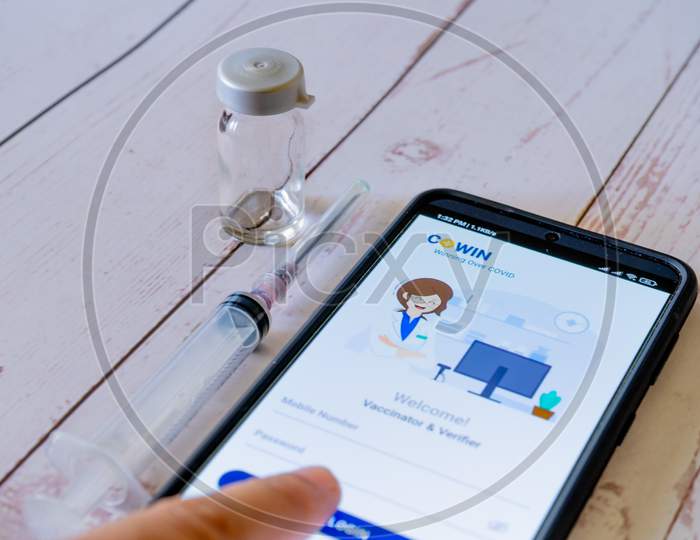 Man Doctor Pointing To Co-Win App Application While Getting Vaccinated With A Syringe And Vial As Covaxin Covishield Is Administered During The Covid19 Coronavirus Pandemic In India Asia