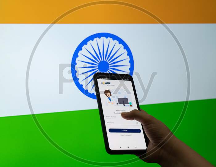 Man Woman Holding The Co-Win Covid19 Coronavirus Vaccination Tracking App Against A Flag Of India As The Innoculation Is Being Done To Ensure Immunity As Cases Surge