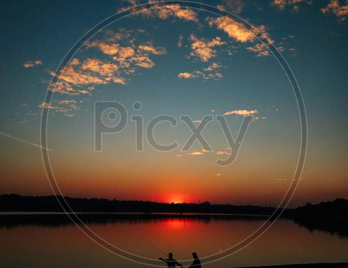 Men fishing in a lake during sunset silhouette picture