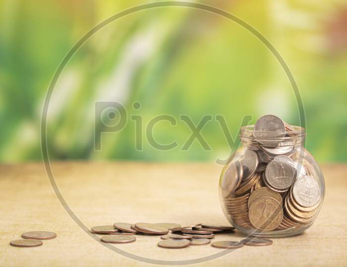 Coin In Glass Bottle With Money Stack