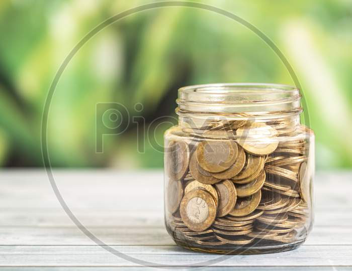 Coin In Glass Bottle With Money Stack