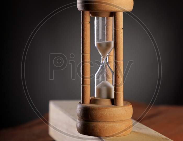 Antique Hourglass Time On Wood Block With Dark Background