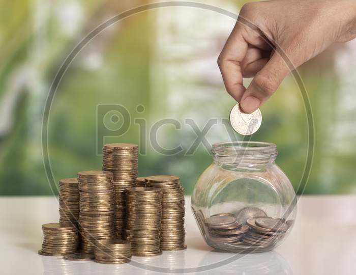 Women Saving Money In A Bottle With Coins