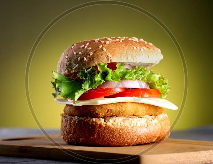 Fast Food - Burger On A Wooden Board And Yellow Background