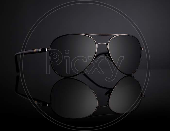 Black Aviator Sunglasses With Reflection On Black Background