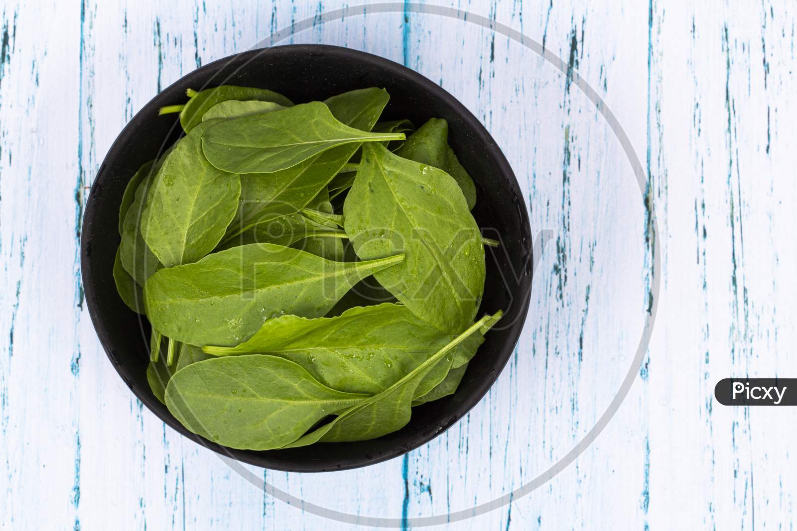 Top View Of Fresh Green Spinach Leaves In Wooden Bowl