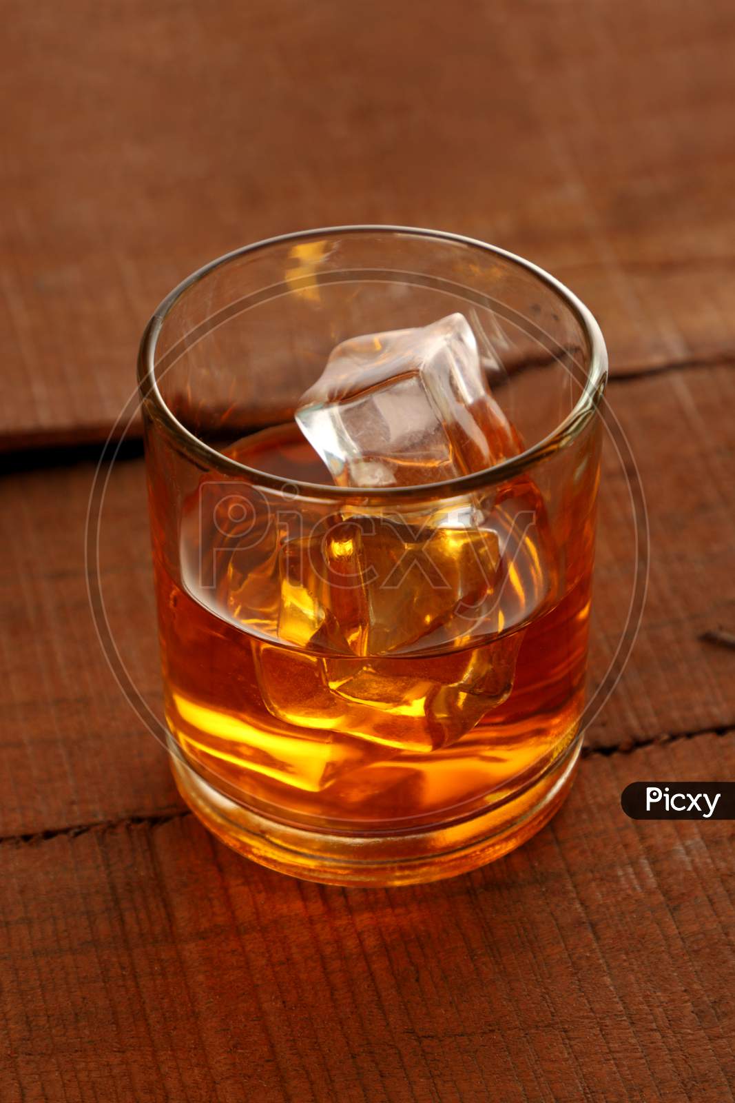 Chilled Whisky Glass With Ice Cubes On Wooden Table