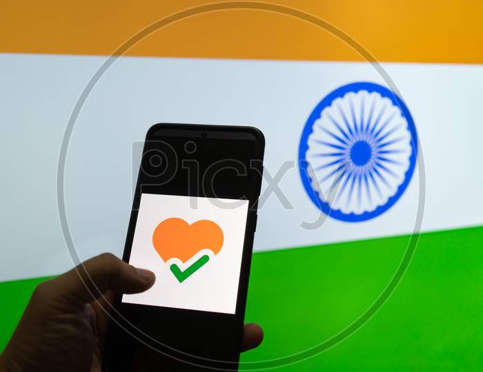 Man Holding Mobile Phone With The Arogya Setu App In Front Of A Flag Of India Showing How Technology Is Helping Contact Tracing In Covid 19 Pandemic