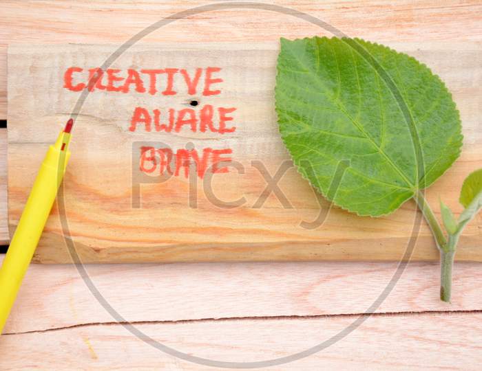 Creative ,Aware,Brave,Write In The Wooden Mental Health Awareness Concept With Green Blue Berry Leaf On The Wooden Background.